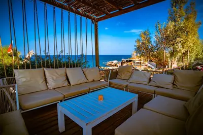 a patio with a couch and a table and the ocean at Malama Beach Holiday Village in Protaras