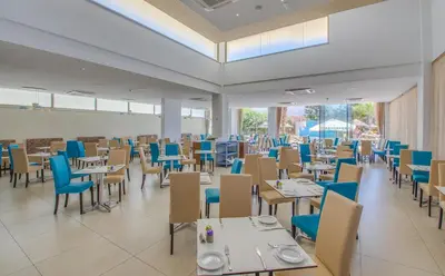 a dining room with tables and blue chairs at Stamatia Hotel in Ayia Napa