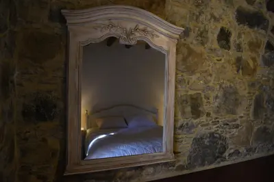 a mirror reflecting a bed in a stone wall at Spiti tis Irinis in Pedoulas