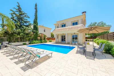 a villa with a swimming pool with chairs and an umbrella at Villa Irina in Paralimni