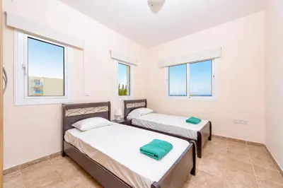 two beds in a room with two windows at Villa Irina in Paralimni