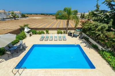 a swimming pool in a patio with chairs at Villa Irina in Paralimni