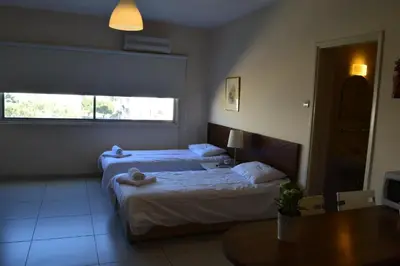 a bedroom with two beds and a table and a window at Lordos Hotel Apts Limassol in Limassol