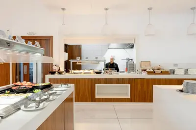 a man standing in a kitchen with a counter at Amethyst Napa Hotel & Spa in Ayia Napa