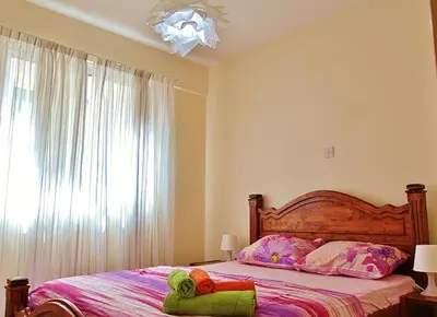 a bedroom with a bed with a large window at Makenzy Apartment in Larnaka