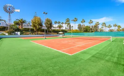 a tennis court with green grass at Nissi Beach Resort in Ayia Napa