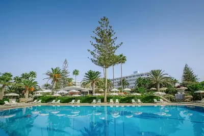 a large swimming pool at a resort with chairs and umbrellas at Nissi Beach Resort in Ayia Napa