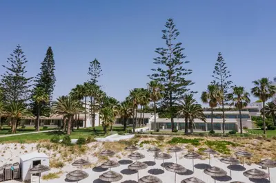 a resort with palm trees and a building at Nissi Beach Resort in Ayia Napa
