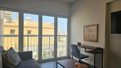 a living room with a couch and a desk and a window at Ha.De.Co. Holiday Apts in Ayia Napa