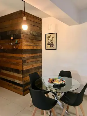 a dining room with a table and chairs and a wooden wall at Fat Cow Apartment 101 in Larnaka