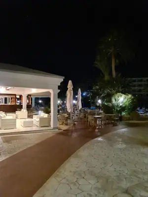 an outdoor patio with tables and chairs at night at Nissiana Hotel & Bungalows in Ayia Napa