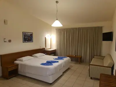 a hotel room with a bed and a chair at Nissiana Hotel & Bungalows in Ayia Napa
