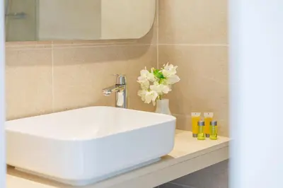 a bathroom with a white sink and a vase with flowers at Nissi Park Hotel in Ayia Napa