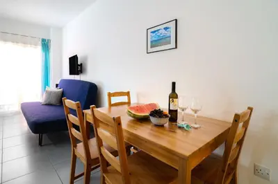 a dining room table with a bottle of wine and wine glasses at Mackenzie Blu Beach Studio in Larnaka