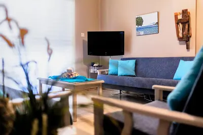 a living room with a blue couch and a tv at Annita Court Block B, Apt6 in Ayia Napa