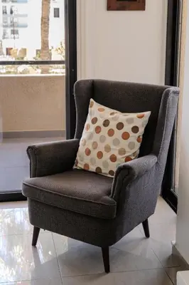 a gray chair with a pillow in a living room at Lazaros Suite Downtown in Larnaka