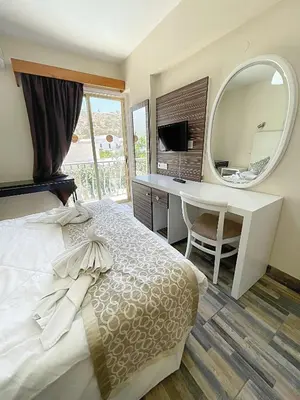 a bedroom with a bed and a desk and a mirror at Antonis G. Hotel Apartments in Voroklini