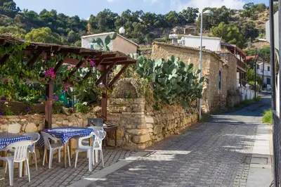 a patio with tables and chairs next to a stone wall at Antonis G. Hotel Apartments in Voroklini