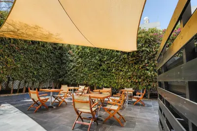 a patio with wooden tables and chairs and a hedge at Vega Apartments in Limassol