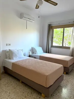 two beds in a room with a window at Himonas Apartments in Pissouri