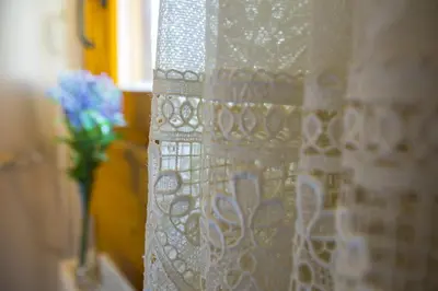 a white curtain with a vase of flowers on a window at Ricky Chalet Near Troodos in Spilia