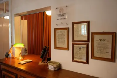 a desk with a lamp and some pictures on a wall at New Helvetia Historic Hotel in Platres