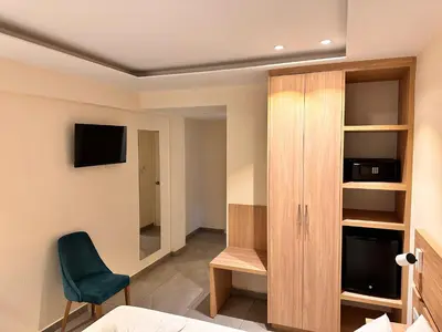 a room with a bed and a chair and a cabinet at San Remo Hotel in Larnaka