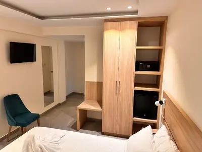 a bedroom with a cabinet and a bed and a chair at San Remo Hotel in Larnaka