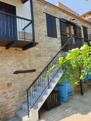 a staircase leading up to a brick building with black doors at Vasilopoulos House in Tochni