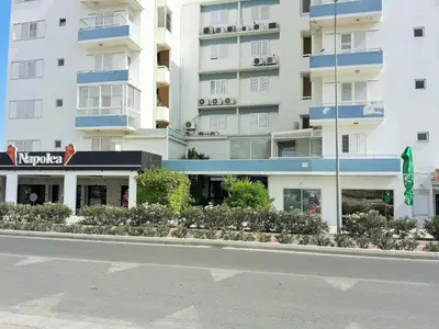 a large white building with blue balconies next to a street at 16 SANDY BEACH in Larnaka