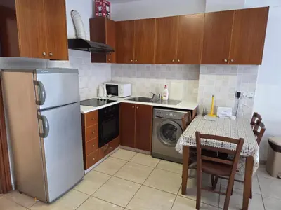 a kitchen with a table and a stainless steel refrigerator at One Bedroom aptm Larnaca in Larnaka