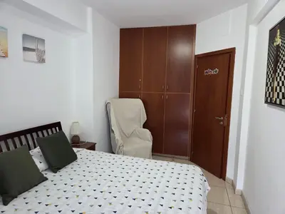 a bedroom with a bed and a chair and a closet at One Bedroom aptm Larnaca in Larnaka