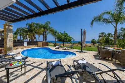 a patio with a pool and chairs and a table at Villa Greco Mare #5 in Paralimni