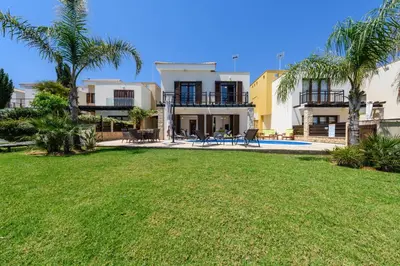a house with a yard with a pool and palm trees at Villa Greco Mare #5 in Paralimni