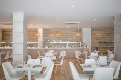a restaurant with white tables and white chairs at Narcissos Waterpark Resort in Protaras