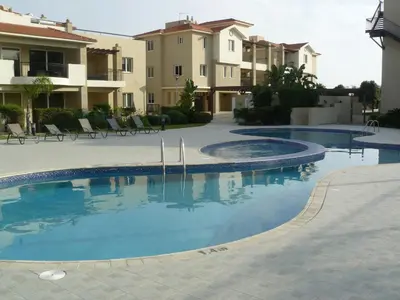 a swimming pool in front of some apartment buildings at Pyla Gardens E107 in Pyla