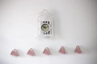a white clock on a wall with four pink shoes at Rimon Cyprus Israeli Kosher Rooms in Larnaka