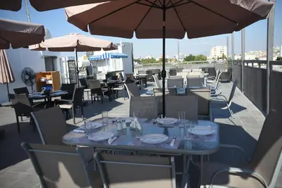 a table and chairs with tables and umbrellas on a roof at Rimon Cyprus Israeli Kosher Rooms in Larnaka