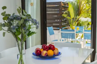 a bowl of fruit on a table with a vase of flowers at Protaras Holiday Villa Alexa in Protaras