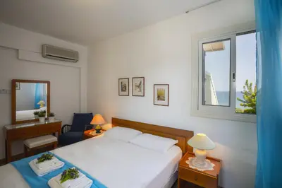a white bedroom with a bed and a window at Protaras Beachfront Sirina Lina Suite in Paralimni