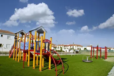 a row of playground equipment on a green field at Mythical Sands Apartments in Protaras