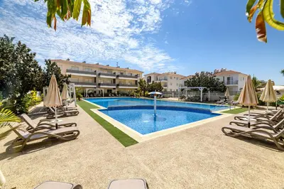 a swimming pool with chairs and umbrellas in front of a building at Mythical Sands Apartments in Protaras
