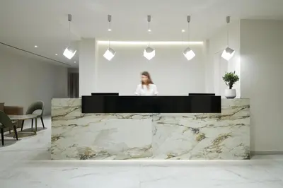 a woman standing behind a marble counter in a lobby at Maris Grand Waterpark Resort in Protaras