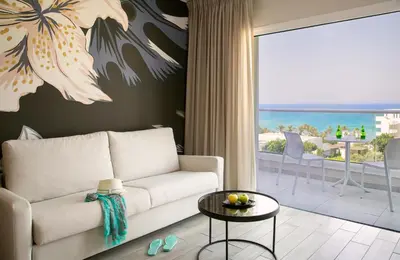 a living room with a couch and a view of the ocean at Vangelis Hotel & Suites in Protaras