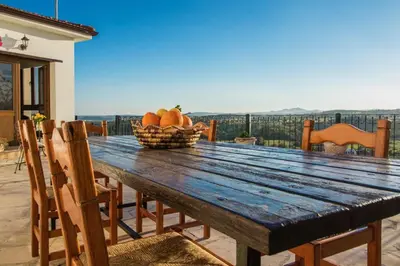 a wooden table with a basket of fruit on a patio at Samareitidos Light Cottage in Anaphotia