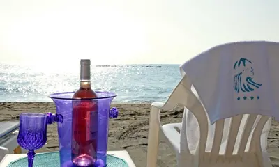 a bottle of wine and a glass on a table on the beach at Poseidonia Beach Hotel in Limassol