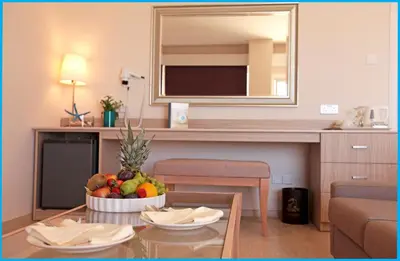 a living room with a table with a bowl of fruit at Poseidonia Beach Hotel in Limassol