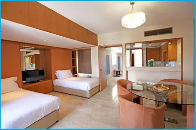 a hotel room with a bed and a dining room at Poseidonia Beach Hotel in Limassol