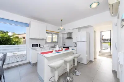 a kitchen with white appliances and a large window at Ayia Triada View in Protaras