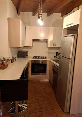 a kitchen with white cabinets and a stainless steel refrigerator at To Apokentro in Alona